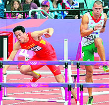 Former Olympic gold medallist China's Liu Xiang (L) falls while competing in the men's 110m hurdles heats on Tuesday