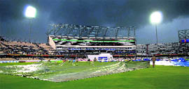 Groundsmen cover the ground after heavy rain stopped play in Hyderabad on Saturday.