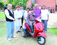 Major Ashok Yadav (retd), chairman, Pathfinder Global School of Pataudi, presents a specially designed scooter to a newspaper hawker at a function in Rewari. Photo by writer