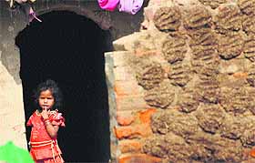 A girl stands outside her hut at a brick-kiln on a sunny day in Karnal.