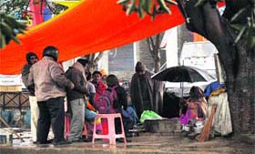 Season�s flavour: People wait to have tea as a vendor sits under a tree during rain in Karnal