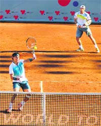 Rafael Nadal, playing a competitive match after eight months, volleys at the net while his partner Juan Monaco looks on in Vina del Mar, Chile, on Tuesday