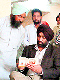 A labourer shows his registration to Judge Daljit Singh after returning from pilgrimage