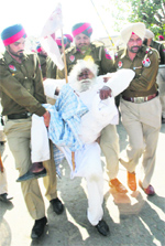 Policemen detain an elderly farmer who along with others was on his way to block a railway track near the Amritsar railway station on Wednesday. Photo: Vishal Kumar