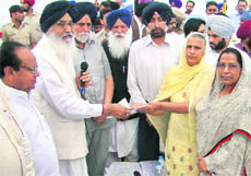 Chief Minister Parkash Singh Badal gives away grants at a Sangat Darshan programme in Mahesari village of Moga on Saturday. Moga MLA Joginder Pal Jain (left) is also seen. 