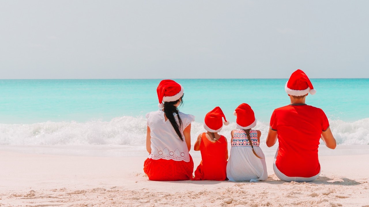 Family sitting on the beach with Santa hats