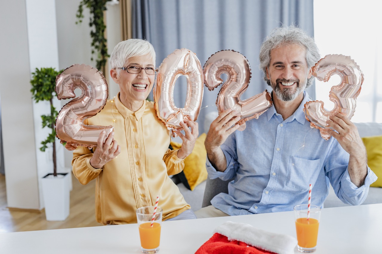 older couple holding 2023 balloons