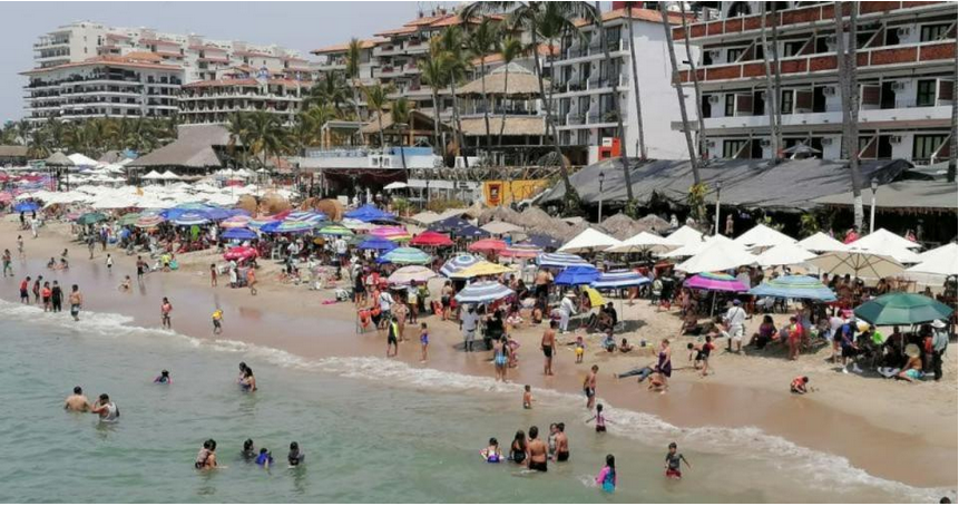 people swimming in the sea by the beach full of umbrellas