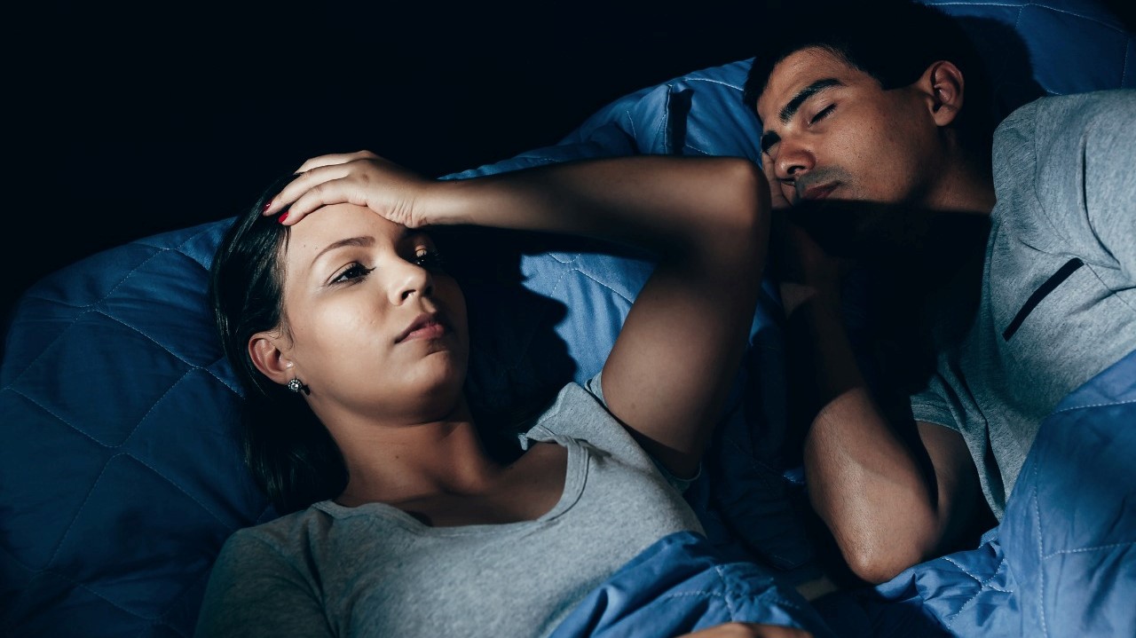 woman with sleeping disorders next to a sleeping man