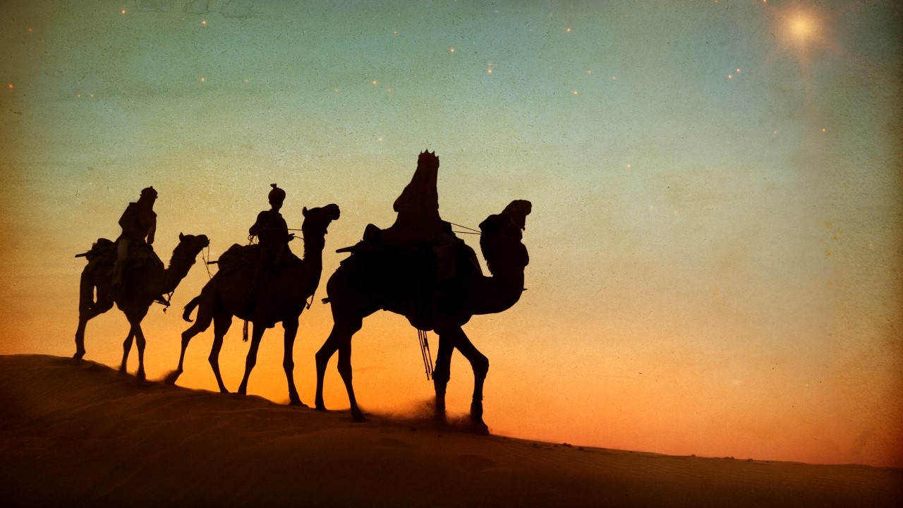 three wise men profiled against orange sky