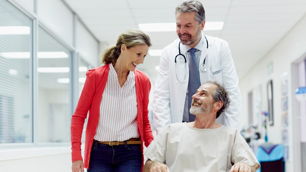 man on wheelchair walking with doctor and wife