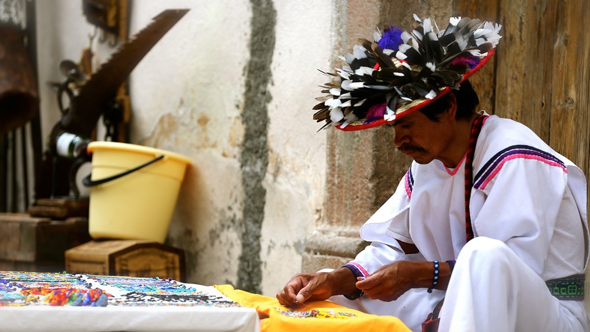 huichol man sitting with his art pieces