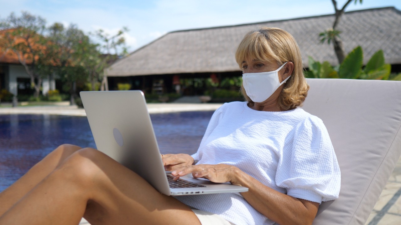 woman sitting by the pool with a laptop