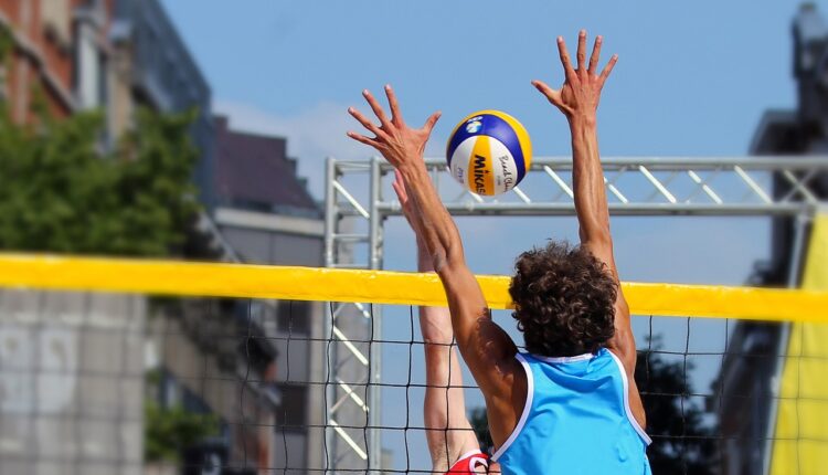 beach volleyball players jumping by the net