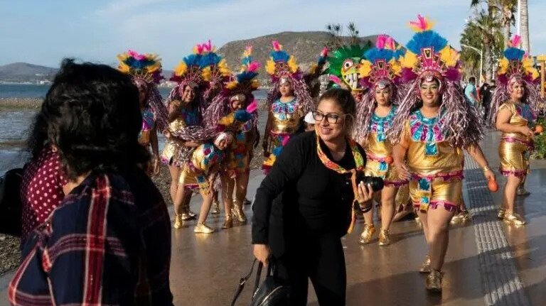 tourists with dancers in the background in Los Cabos fiestas