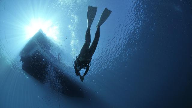 Diver under a boat in blue water
