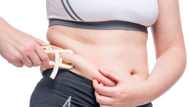 fat woman measures the level of fat on the abdomen tool