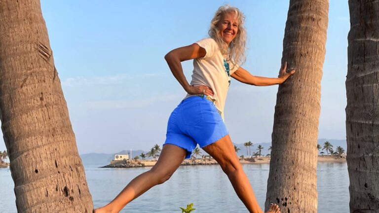 heidi Heckler standing on the trunk of two palmtrees