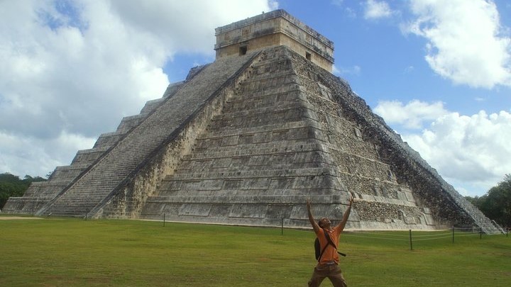 Man standing raising his arms in front of Chichen Itza pyramid