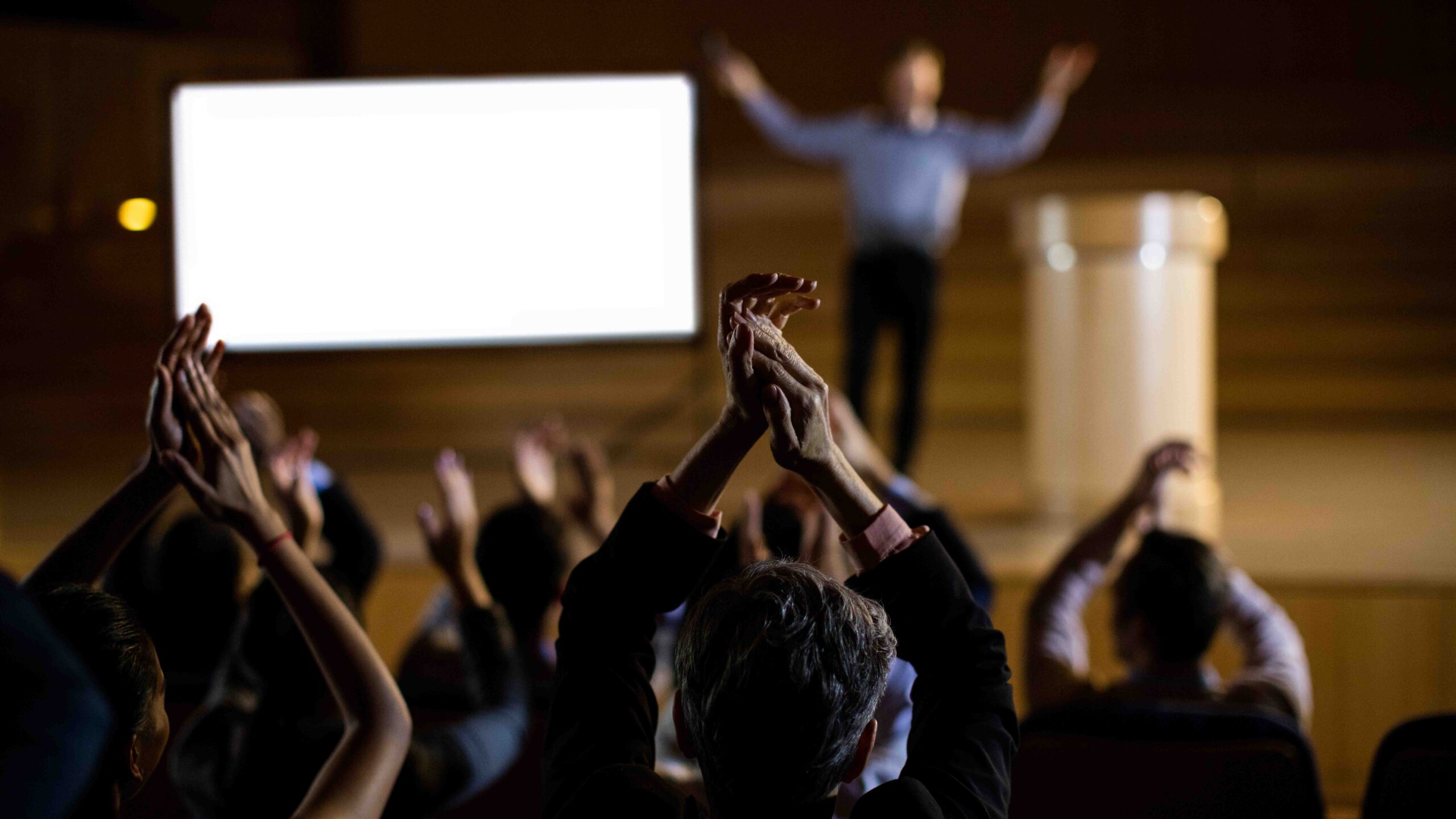 Crowd applauding a public speaker at a conference