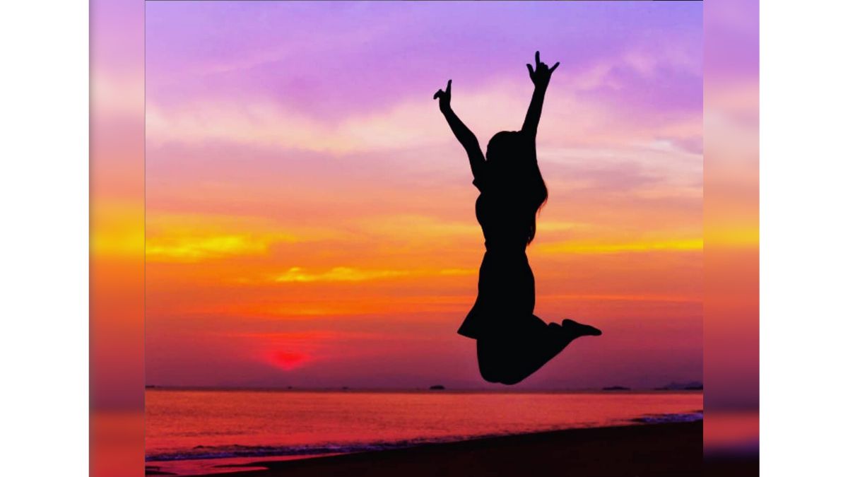 Woman jumping with a red and purple horizon behind.