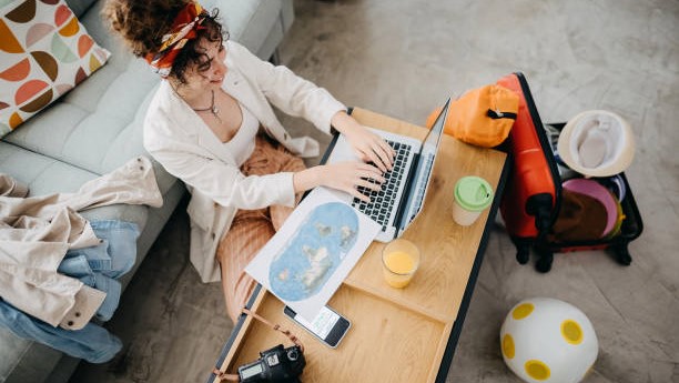 Woman preparing for road trip, planning on the laptop