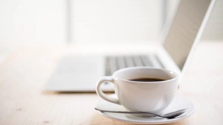 A coffee cup with a laptop on the background.