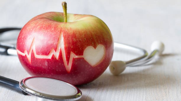 Heartbeat line on red apple and stethoscope, healthy heart diet concept background