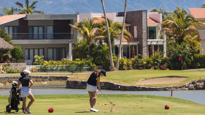 An exquisite view of El Tigre Golf and Country Club, a golfer's paradise. In this image, two ladies relish a game of golf on the renowned award-winning course, set against the backdrop of elegant homes that exemplify the luxury and sophistication of this golfing community.