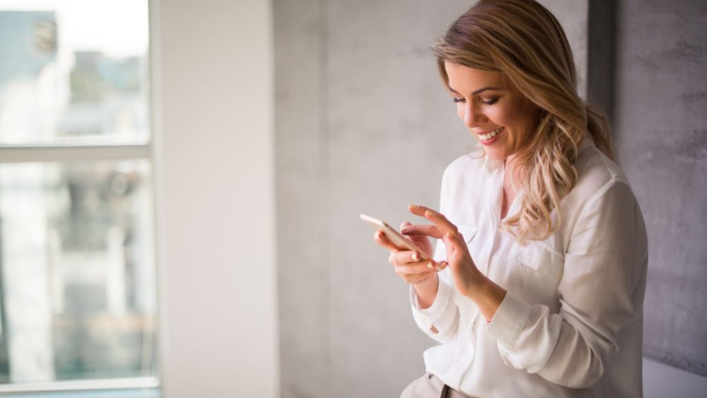 Woman by a window using her mobile telephone