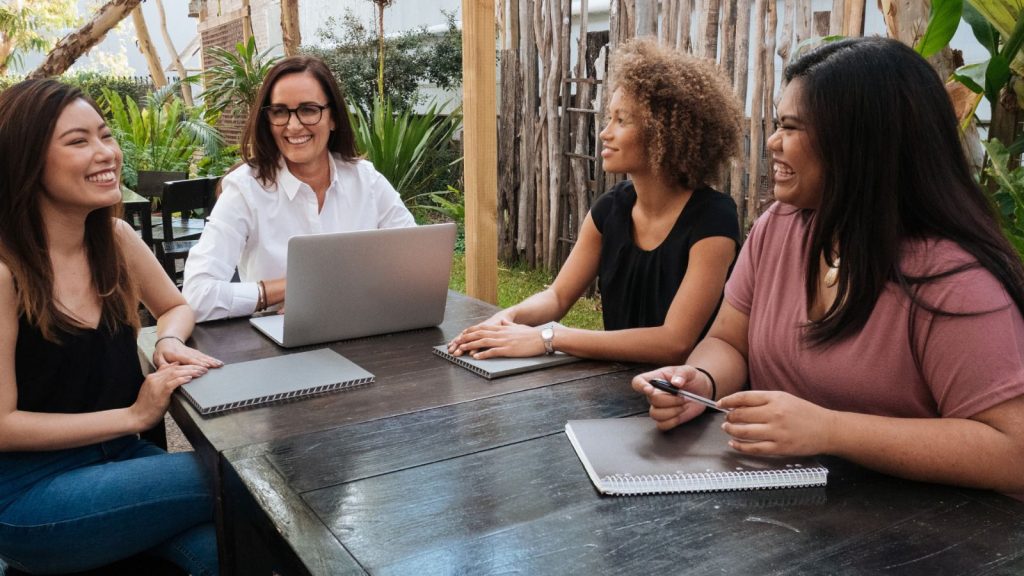 Women at a table working on their laptops