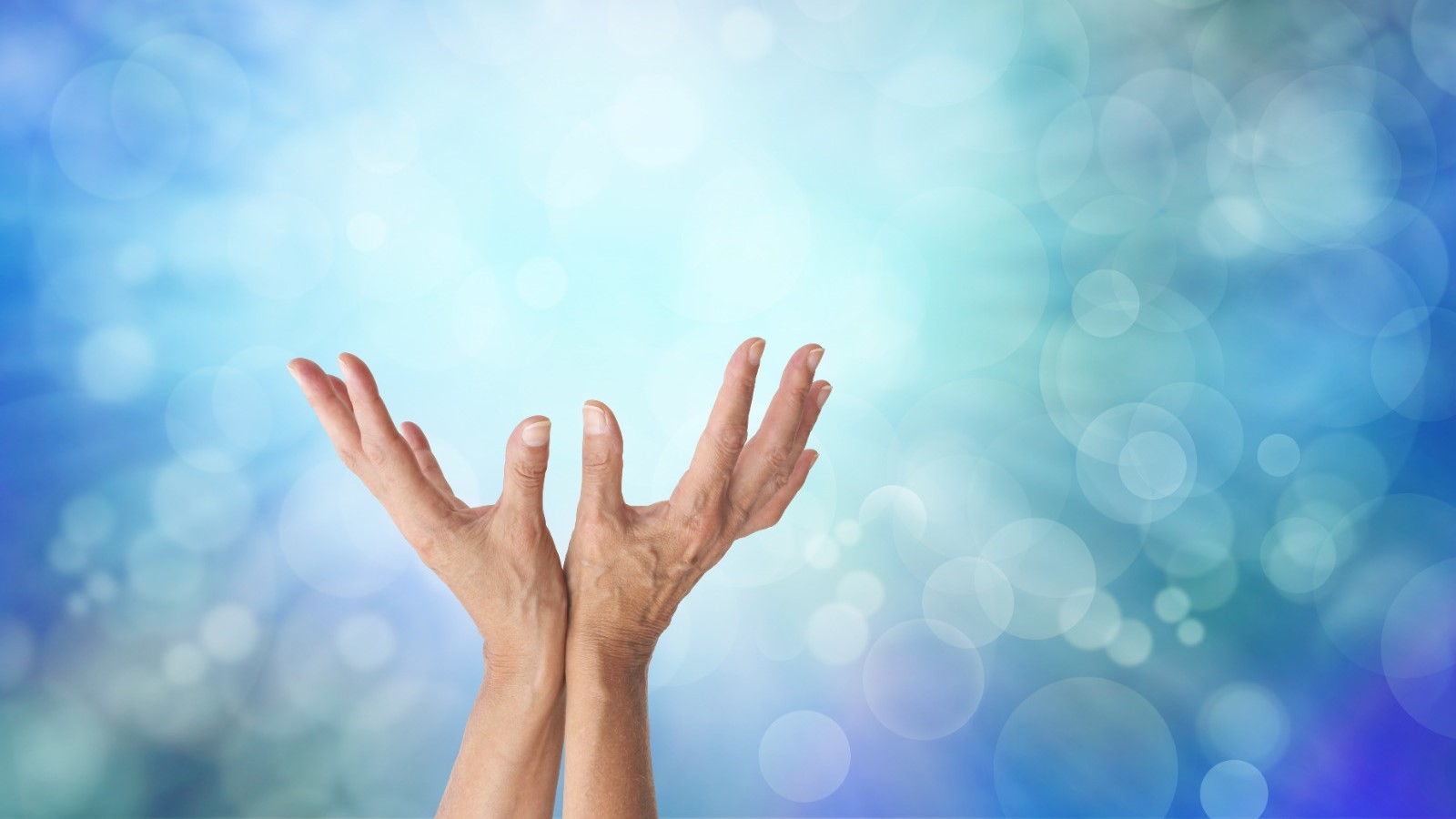 Hands reaching out to the sky with blue light