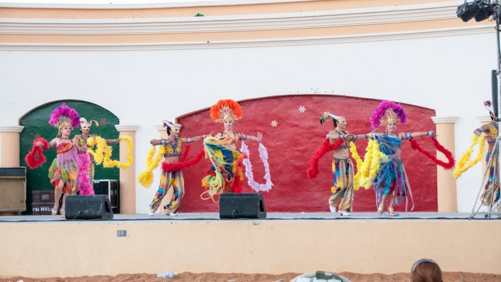  In front of an impressive edifice, a group of dancers execute a captivating performance on stage