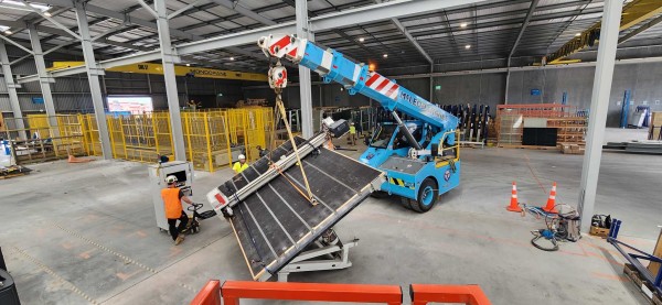 A blue McLeod Crane, lifting a heavy metal platform 
