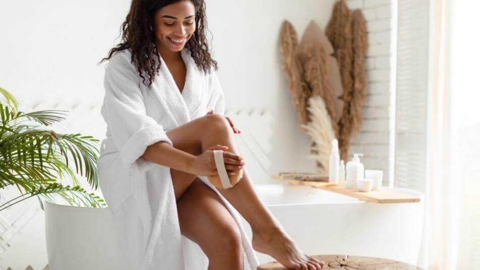 Woman dry brushing her skin in the bathroom