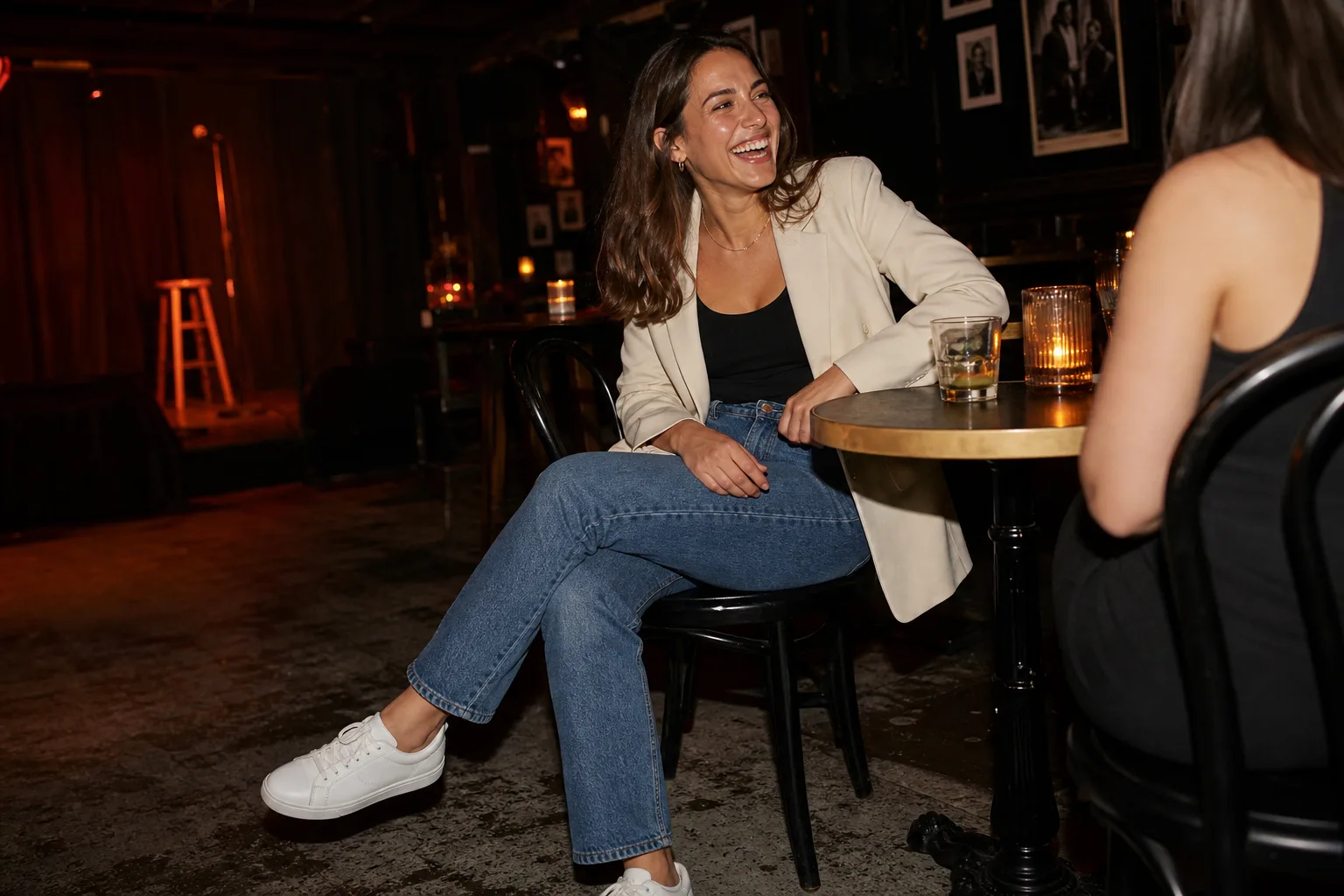 Cream blazer with a black top, straight-leg blue jeans, and white sneakers