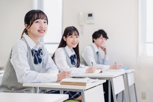 高校生が勉強している様子。女子二人と男子一人が興味深そうに勉強している。