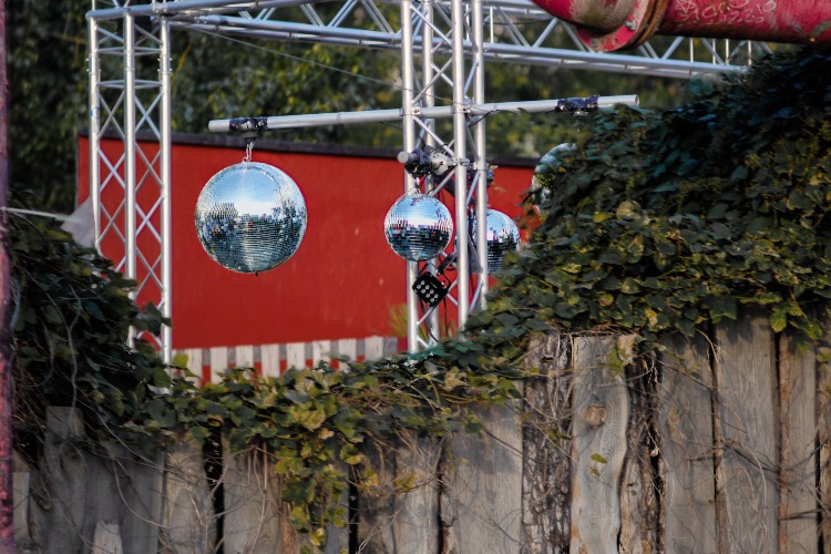 Disco balls hanging in front of a club's red wall in Berlin, Germany