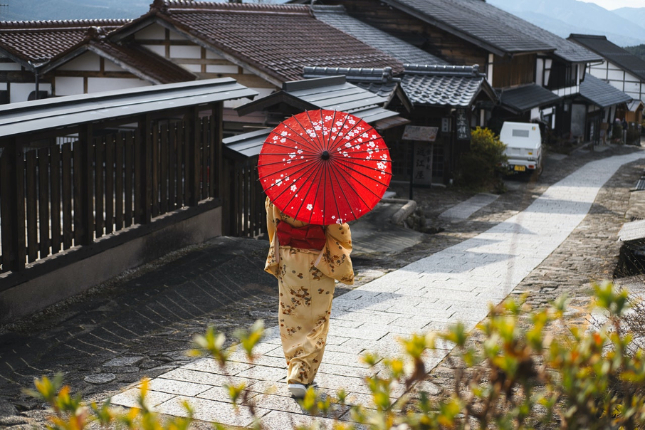 Woman in Japanese attire walking through a Japanese neighborhood with wagasa umbrella