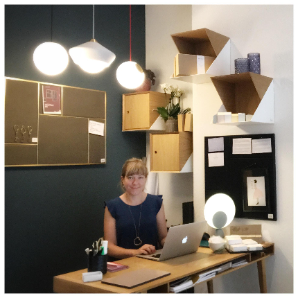 Julie Marie Kjersem sitting behind her desk in front of a blue wall