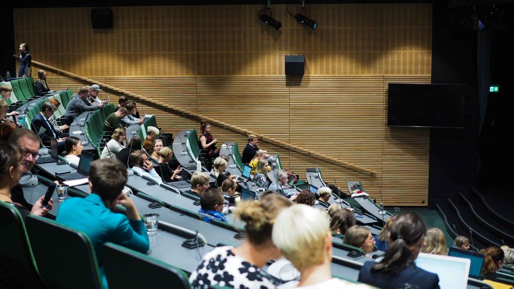 Auditoriossa istuvia ihmisiä 