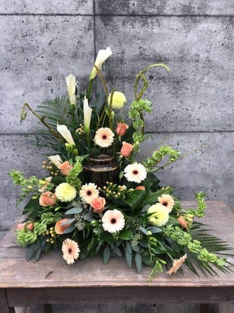 The Watering Can | A lovely peach and blush spray behin the urn that fully embraces the urn.