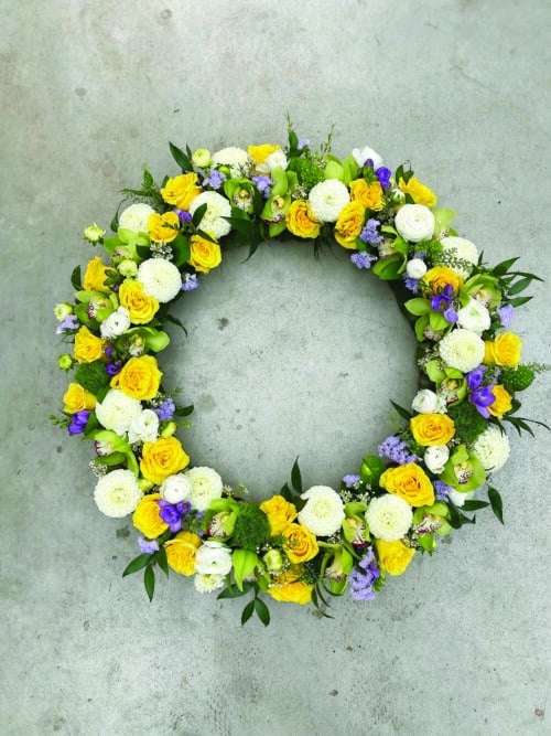 The Watering Can | A large yellow, white, and purple floral wreath.