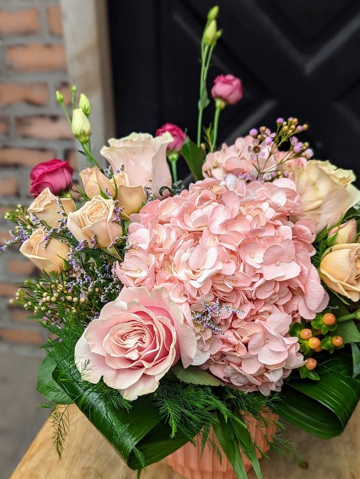 The Watering Can | A pink hydrangea. roses, and lisianthus in an all pink bouquet in a coral ceramic vase.