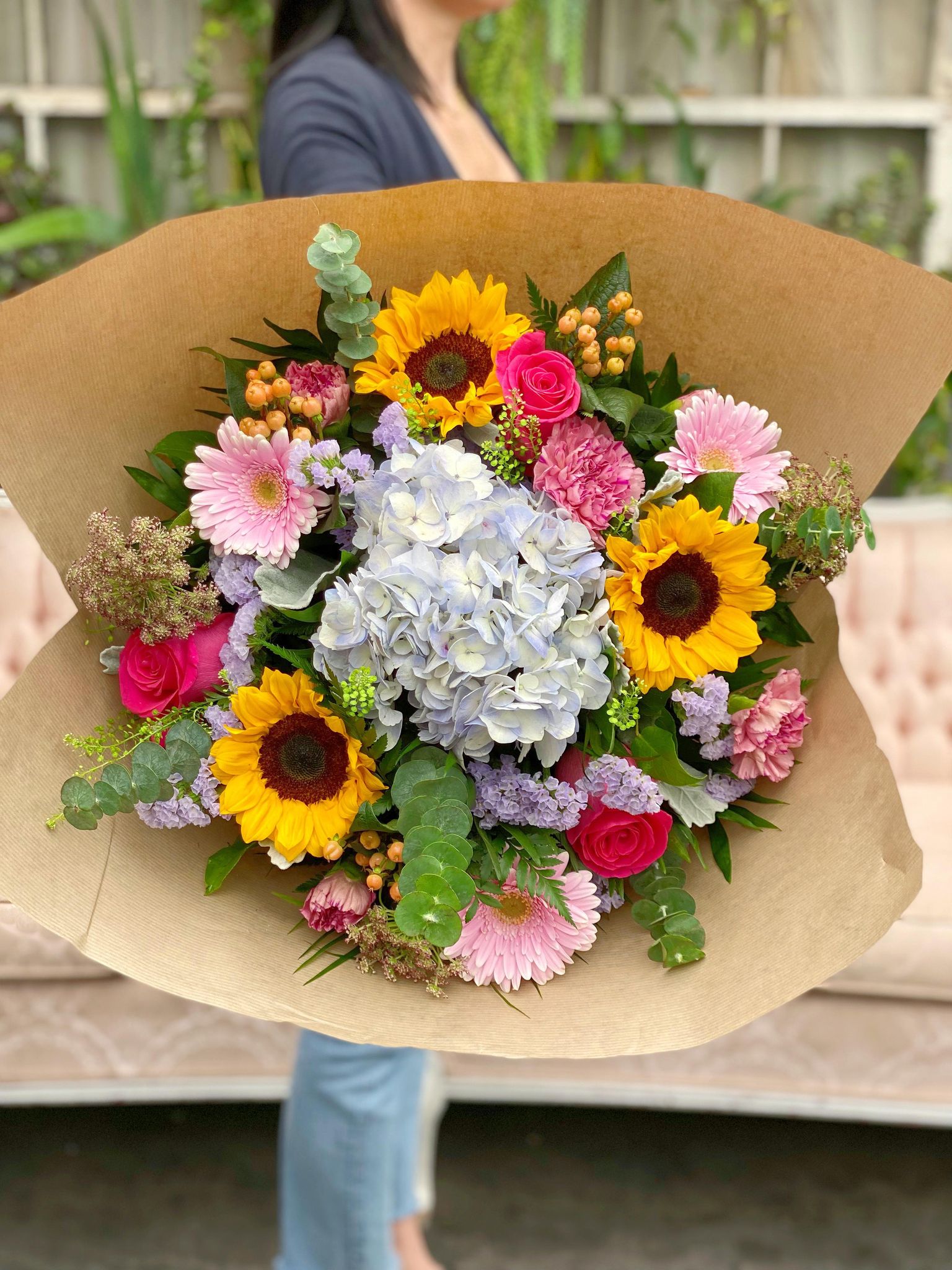A lage gardeny hand-tied bouquet with lavender hydranea, sunflowers, roses, and gerberas.