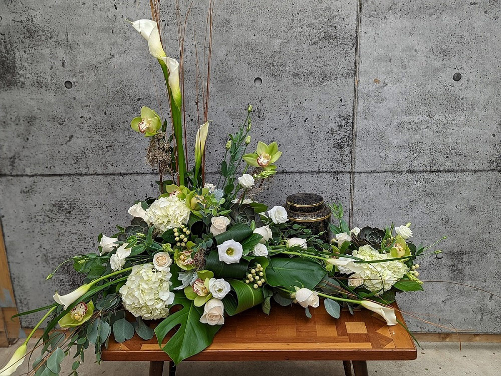 A Stunning white and creamtion arrangement freaturing calla lilies, hydrangea, and orchids.