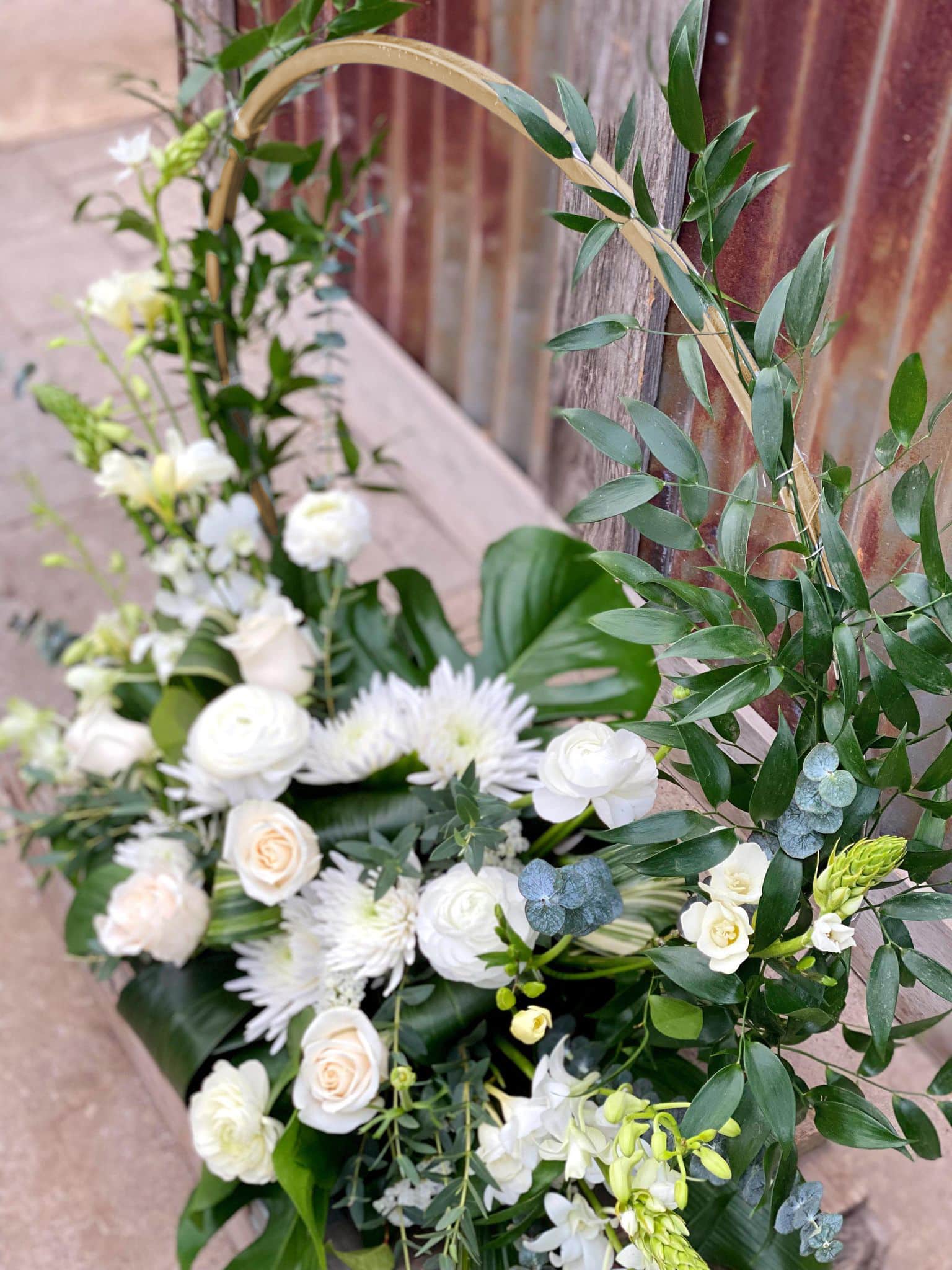The Watering Can | View from above of a large European style floral arrangement of white flowers growing up along a golden hoop.