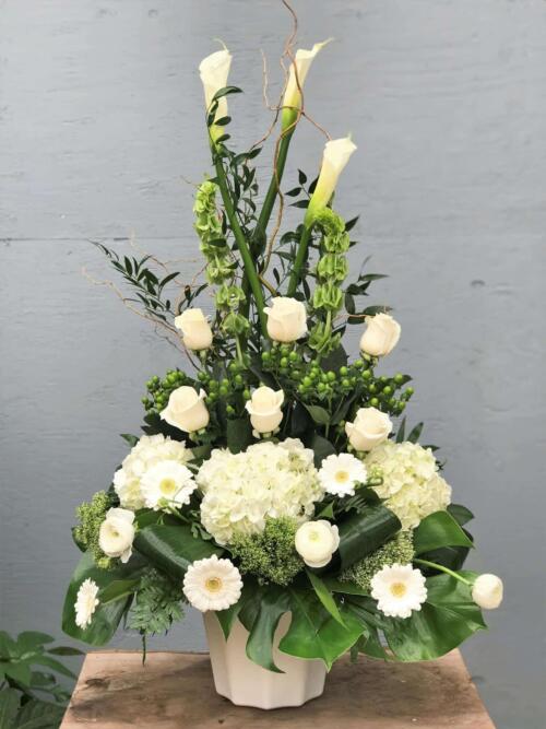An all white side spray made with calla lilies, bells of Ireland, roses, hypericum, hydrangea, trachelium, gerberas, rununculus, curly willow and a variety of greens.