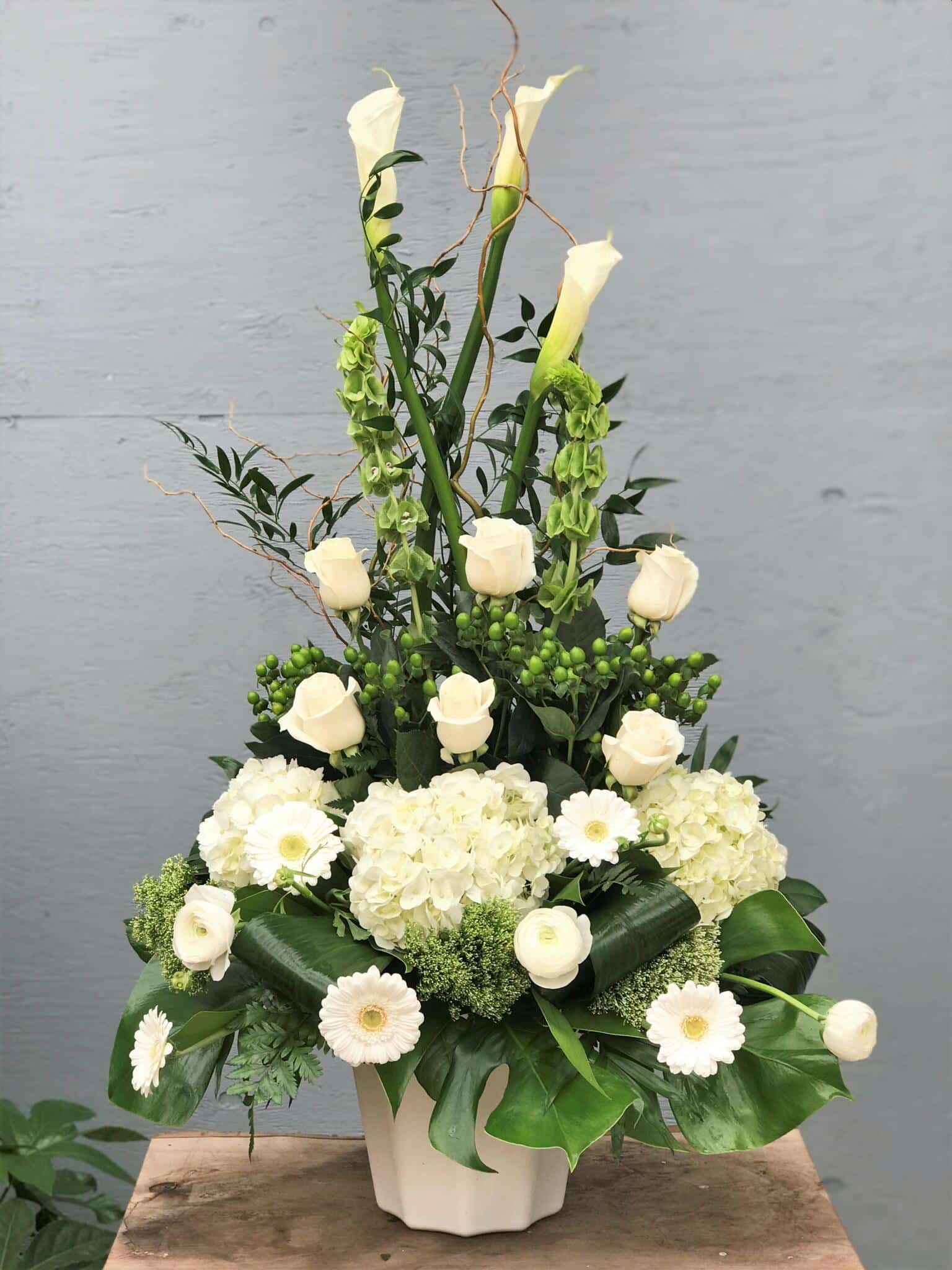 An all white side spray made with calla lilies, bells of Ireland, roses, hypericum, hydrangea, trachelium, gerberas, rununculus, curly willow and a variety of greens.