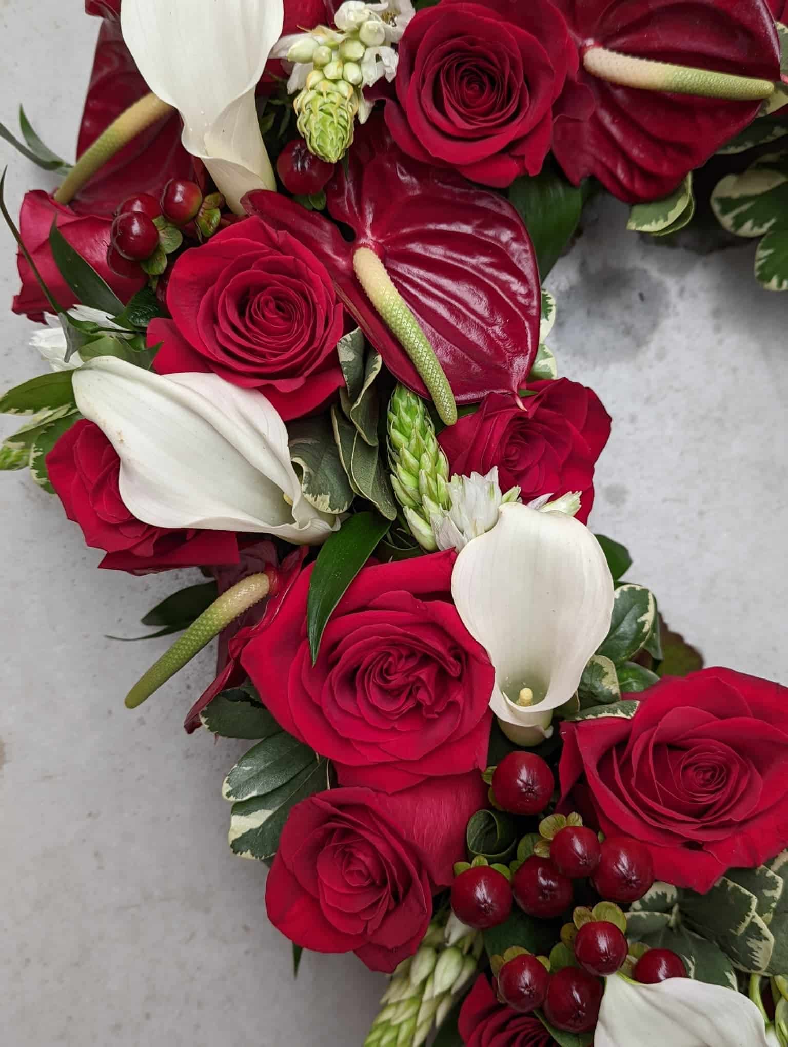 Close up of roses, calla lilies, and anthuriums in a heart shaped floral arrangement.